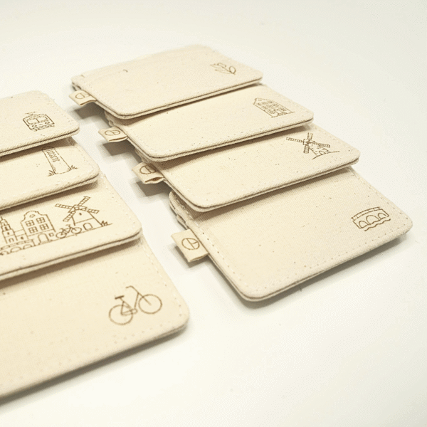 Angled side view of 8 handmade CARDHEIR cardholders featuring engraved Amsterdam cultural icons – sustainable canvas wallets