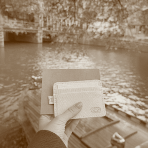 Handmade kraft envelope with laser-marked Omafiets bicycle icon, held in hand by Amsterdam canal.