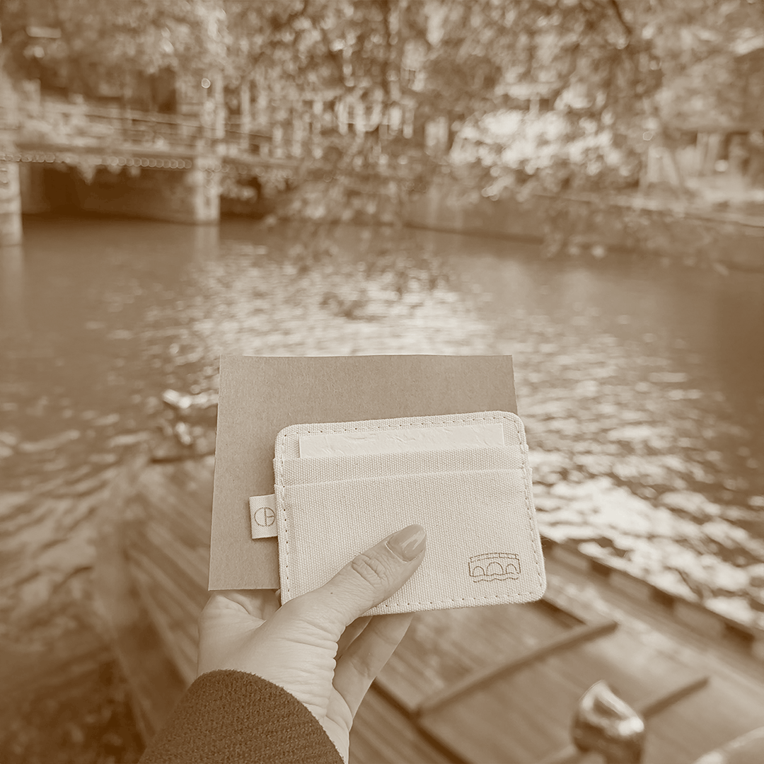 Handmade kraft envelope with laser-marked Omafiets bicycle icon, held in hand by Amsterdam canal.