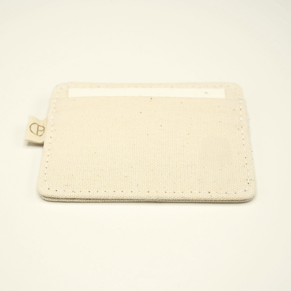 Minimal canvas cardholder by CARDHΞ↓R, shown in use with a visible card inside the top slot and a subtle side tab logo.
